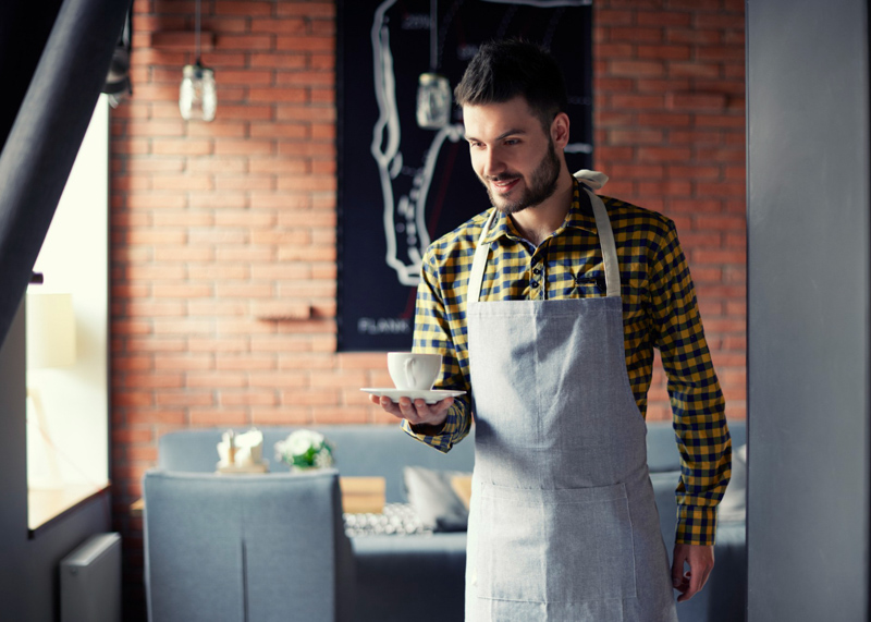 young waiter serving cup of coffee